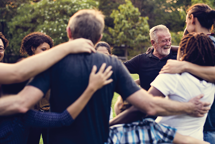 Older man laughing with a group of people in a circle.