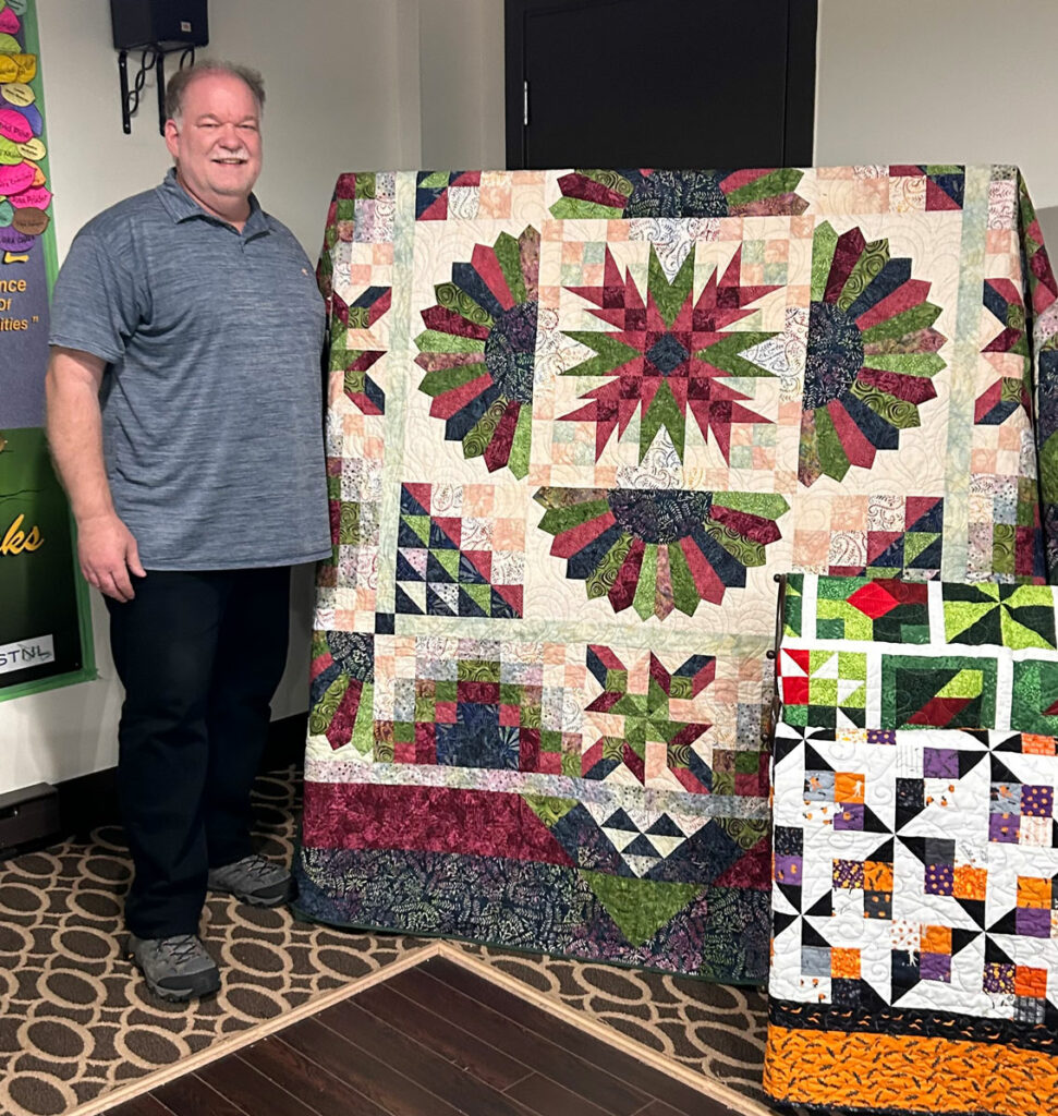 Scott Thistle posing with his homemade quilt